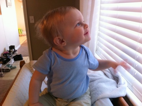 He is fascinated by the blinds next to the changing table. 